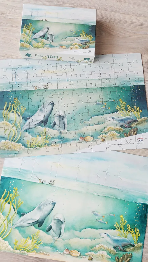 Na blacie leżą puzzle z ilustracją akwarel ową przedstawiającą podwodne życie zwierząt morskich, autorka ilustracji Agnieszka kierat Stadnik.
